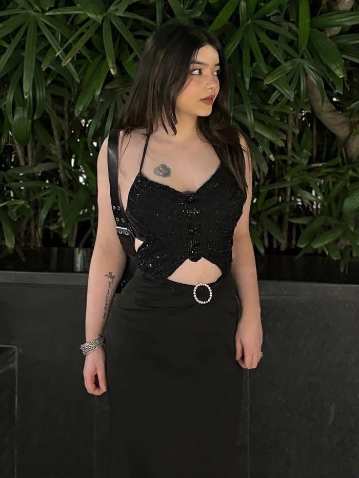 Woman in a black outfit standing in front of green foliage